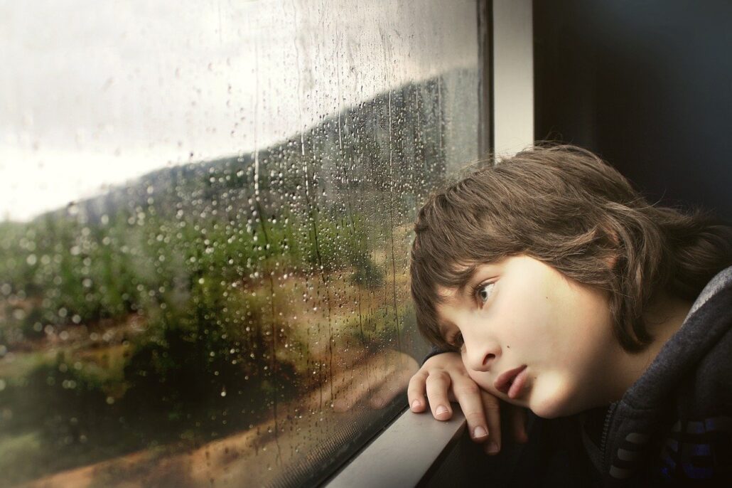 Niño en ventana de PVC viendo llover